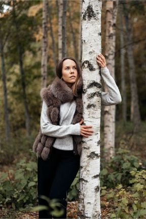 nainen metsässä yllään tummanruskea turkisliivi